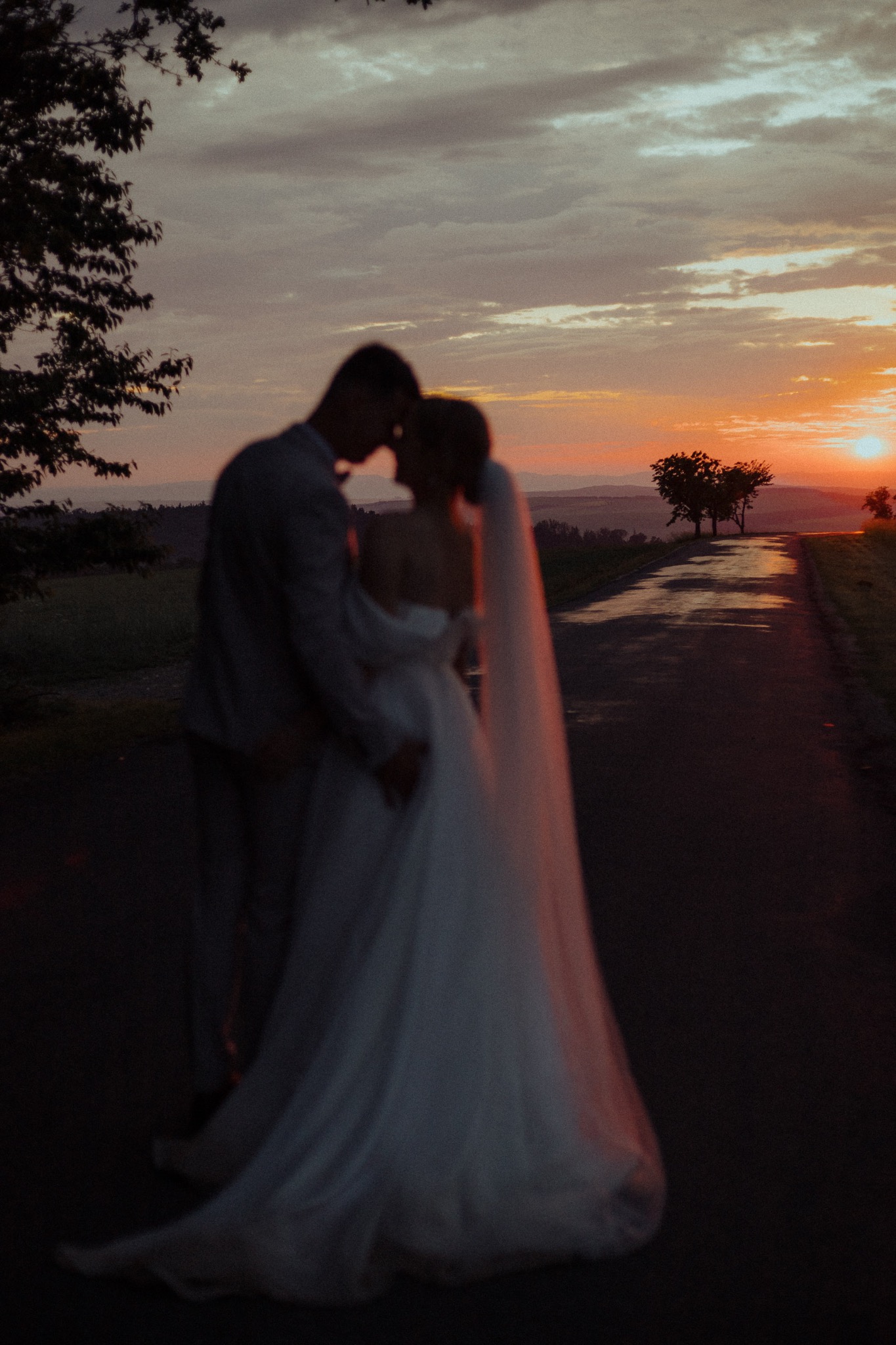 A softly blurred silhouette of newlyweds before a red sunset